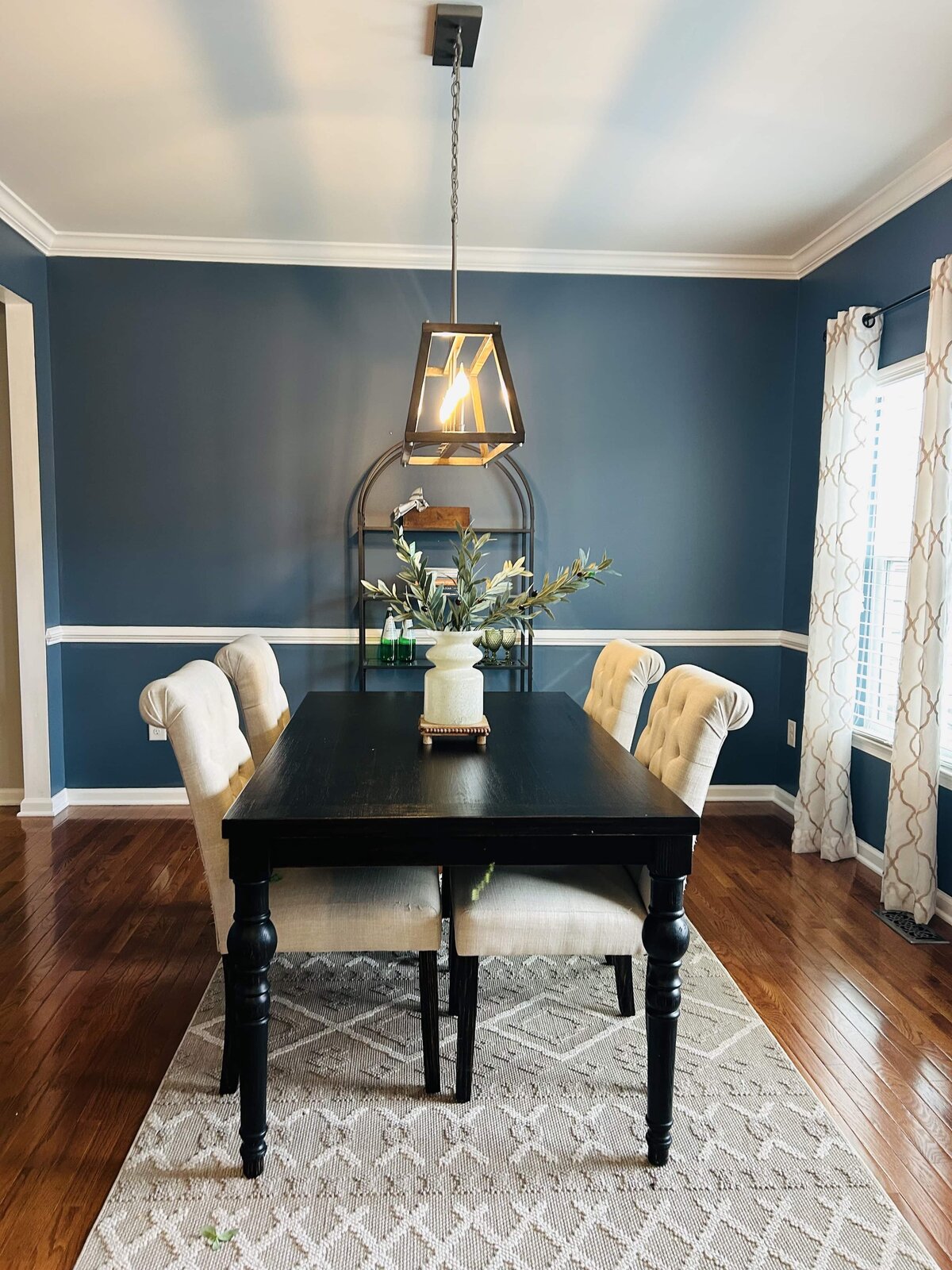 Staged dining room with dark blue walls, wooden table, and upholstered chairs — Williamsburg home staging project.