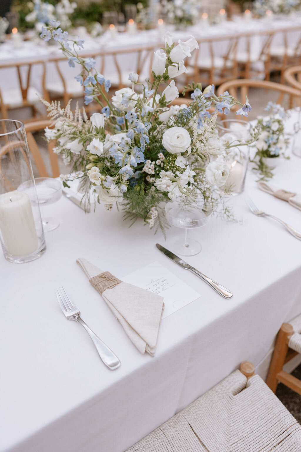 Wishbone chairs and long rectangle reception table with blue and white flowers on top