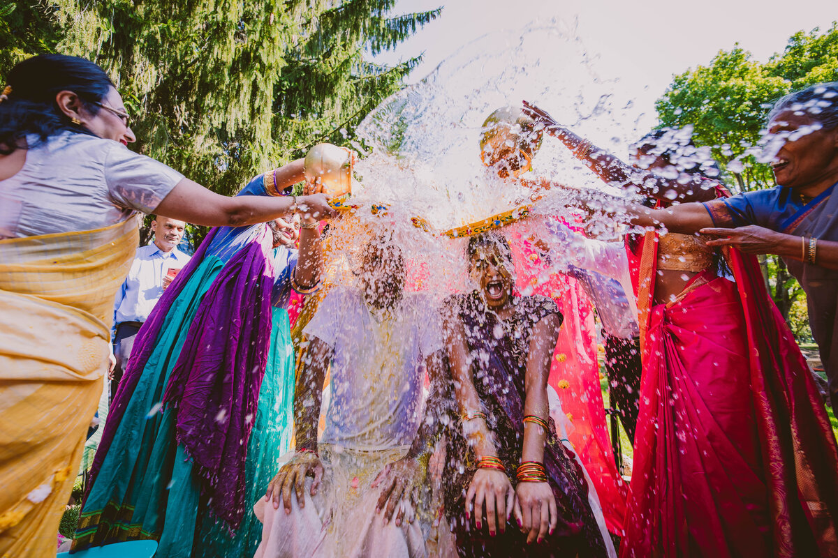 Indian bride and groom having water poured on them after their traditional telegu haldi ceremony during the wedding week