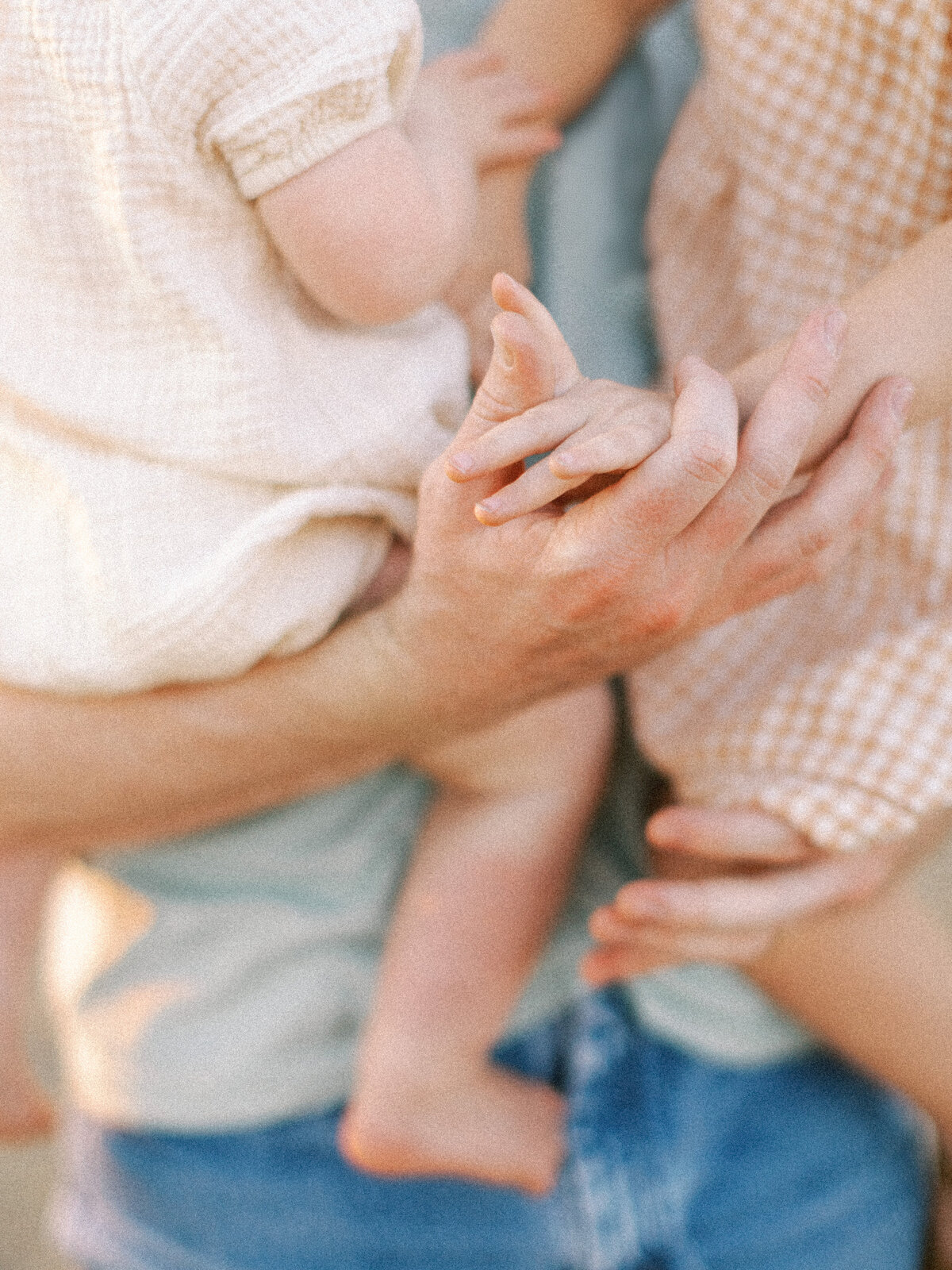 dad holds two toddlers and holds hand of one of them