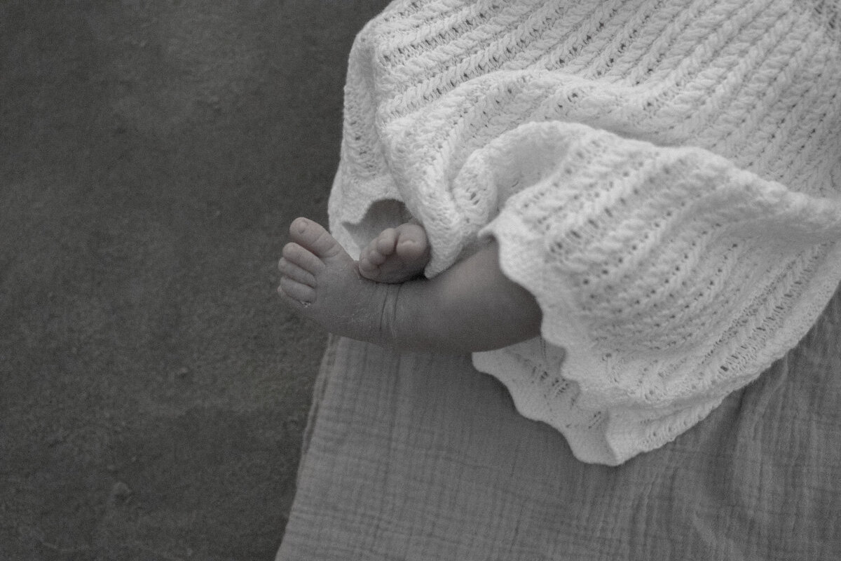A baby's tiny feet wrapped in a soft knit blanket