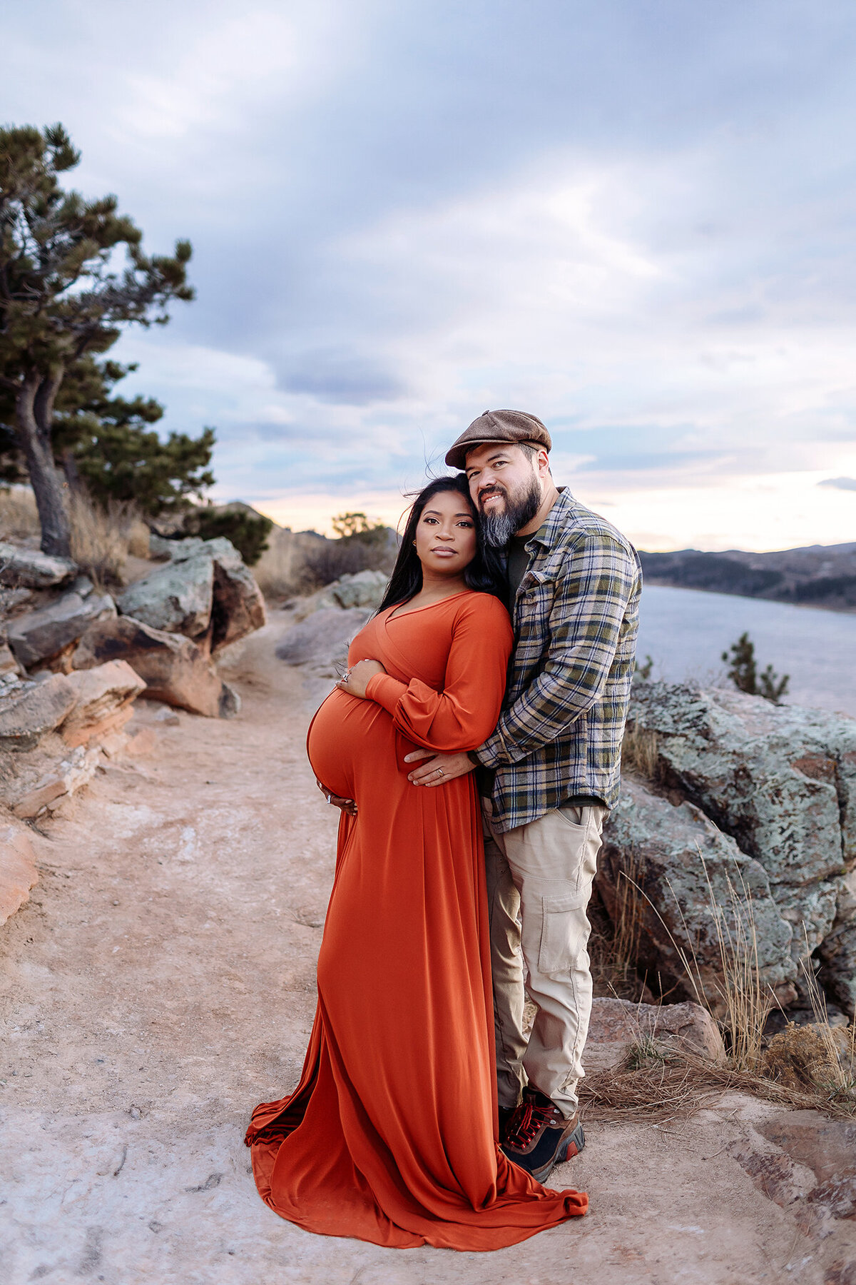 longmont couple poses along dramatic mountain overlook in fort collins at sunset with the maternity photographer capturing the moment