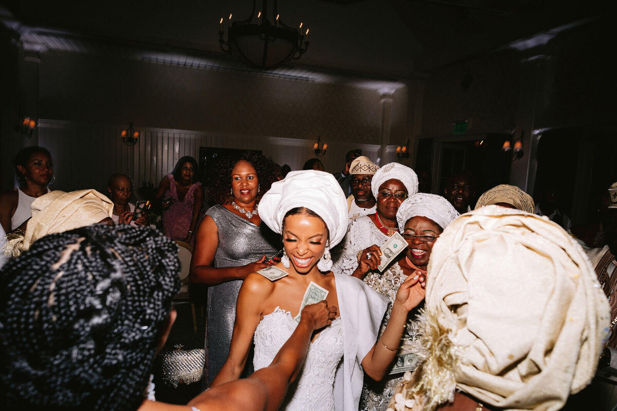 The bride is wearing a traditional African head wrap while doing money dance in Montage at Palmetto Bluff. Image by Jenny Fu Studio