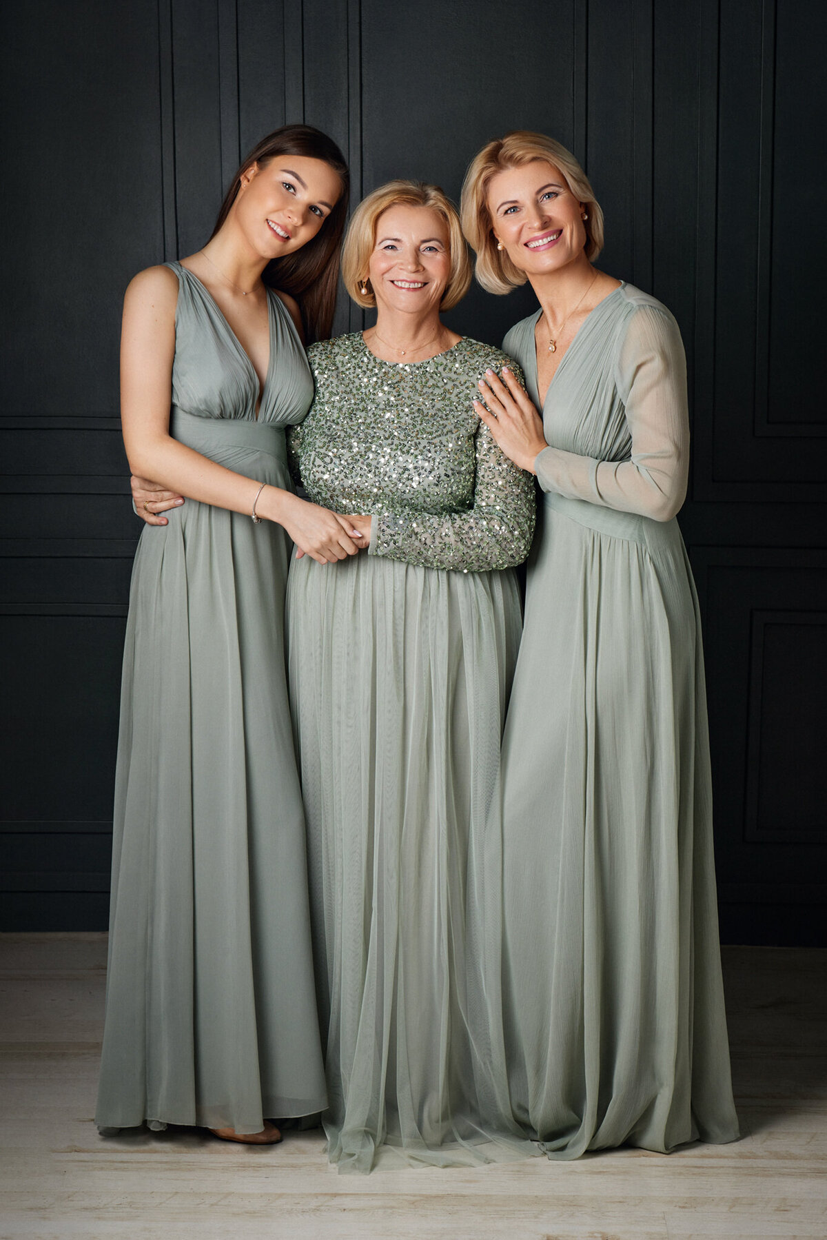 A portrait of smiling three beautiful women of three generations on dark green background