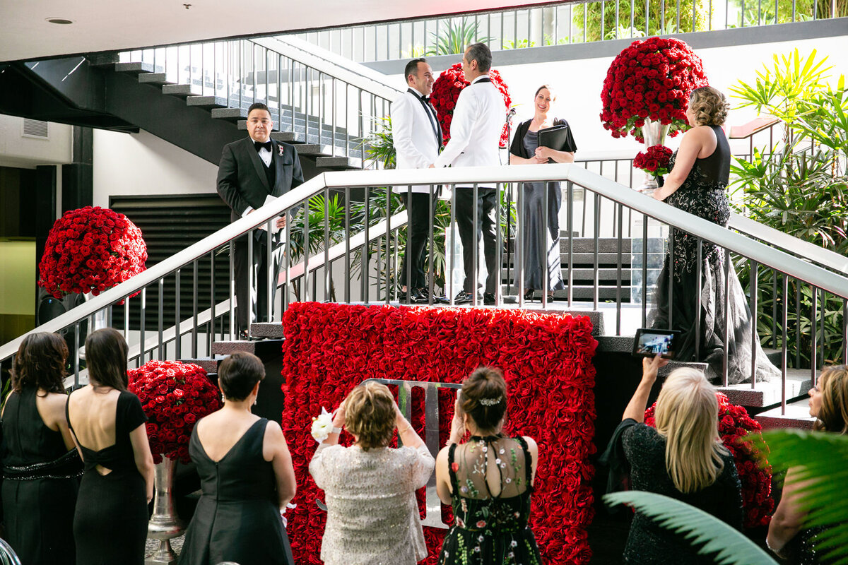 Two grooms standing a the top of a staircase holding hands