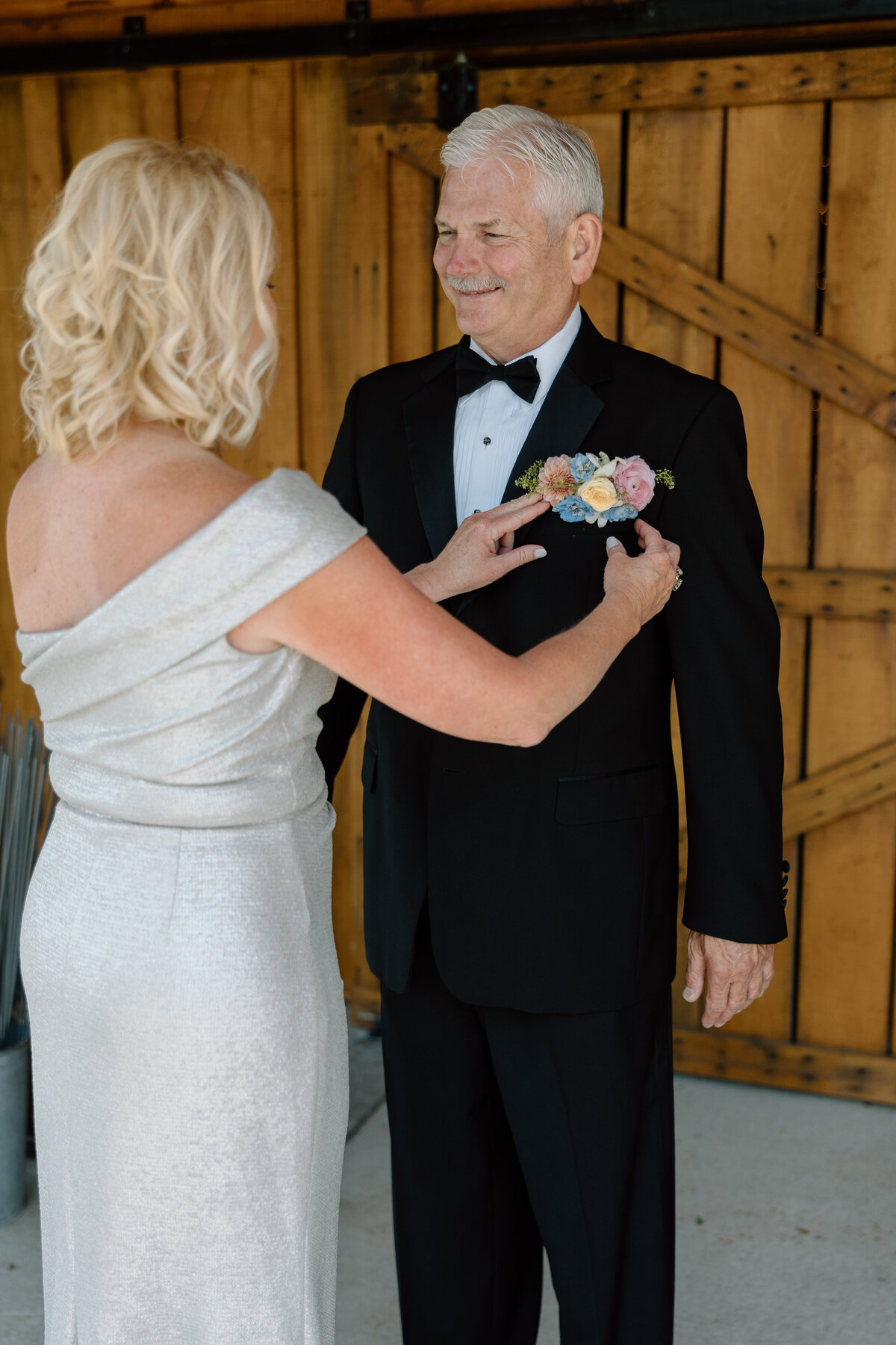 Mother of the bride adjusts father of the bride's Boutonniere
