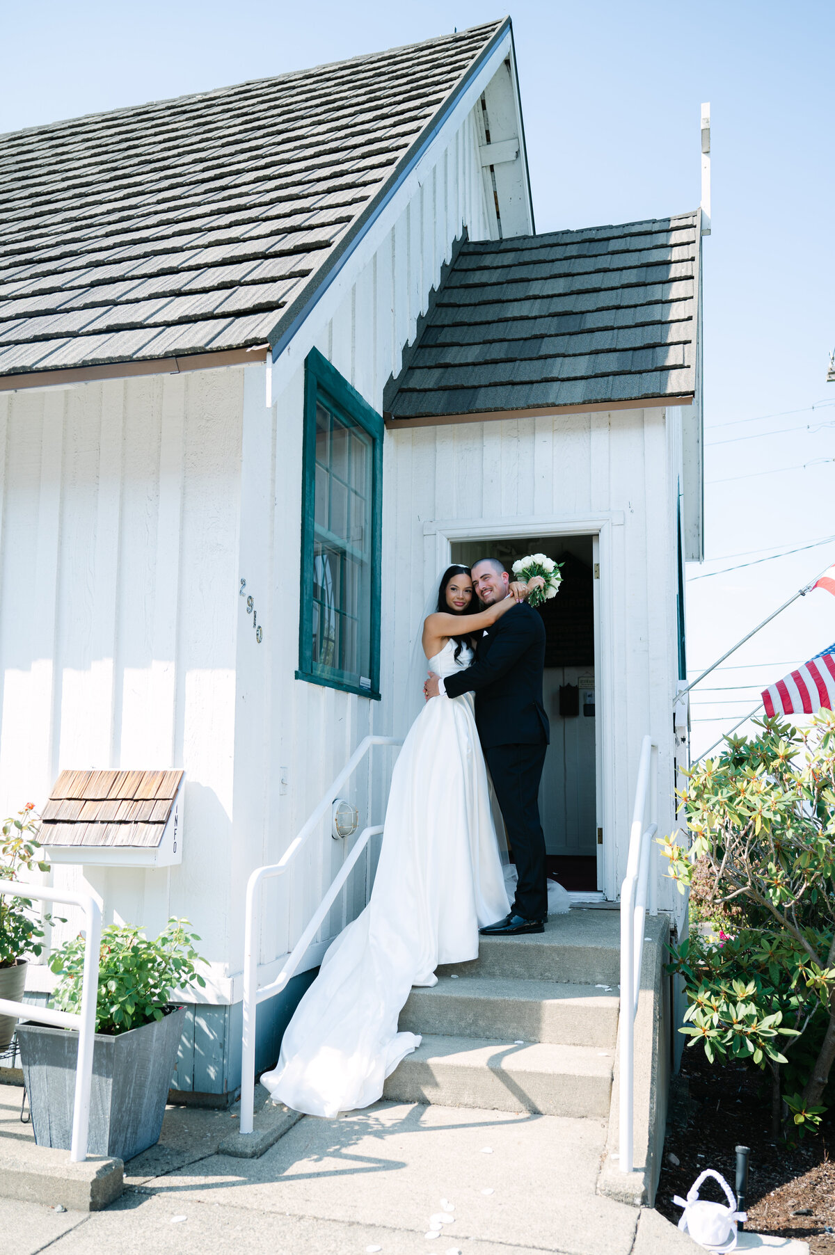 happy bride and groom pose outside of white chapel in tacoma post ceremony