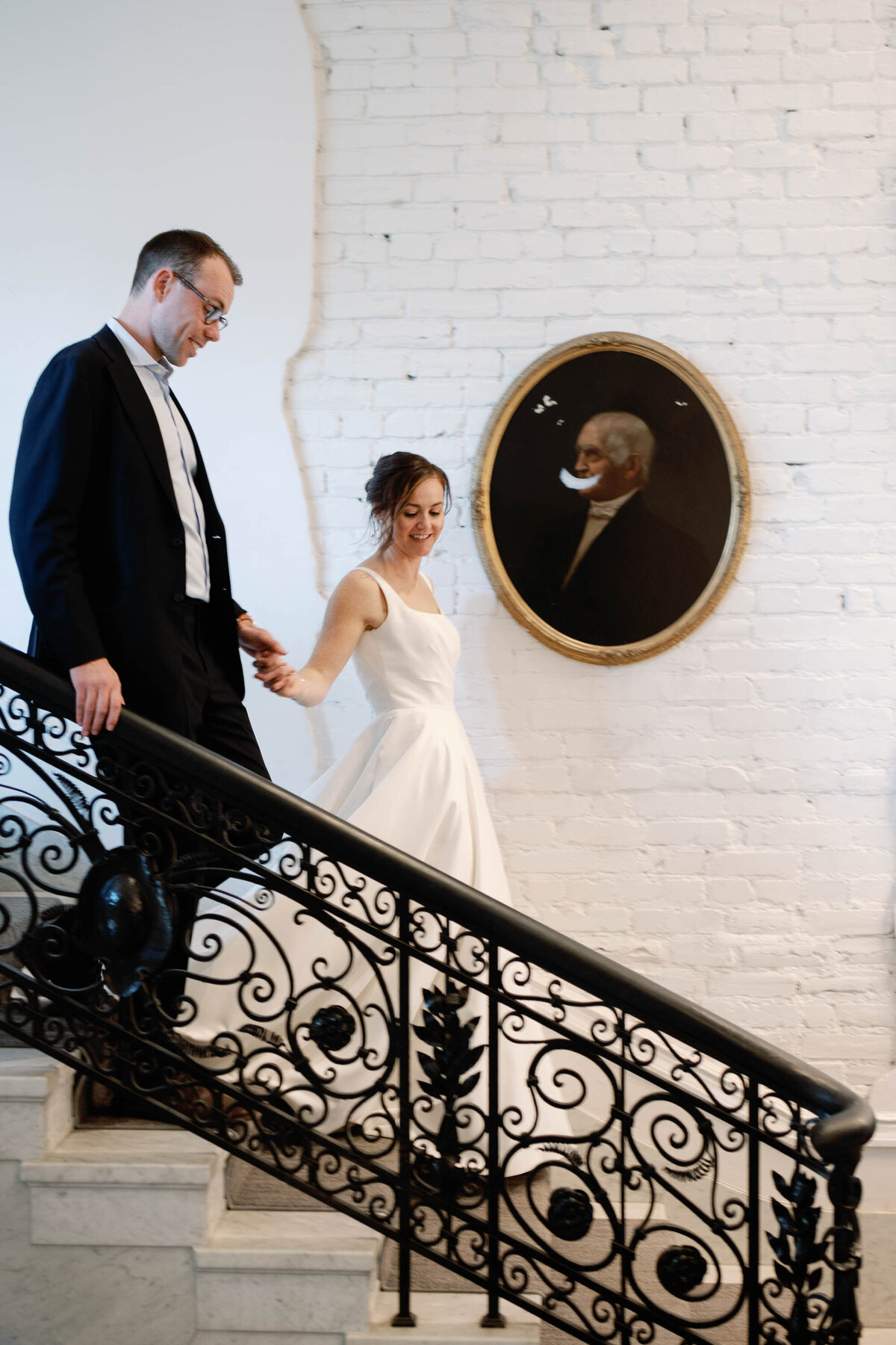 bride and groom at Washington DC wedding descend staircase at patterson mansion