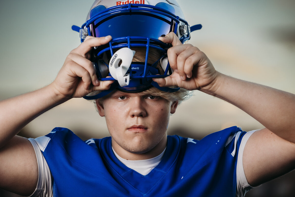 High school football player taking off helmet.