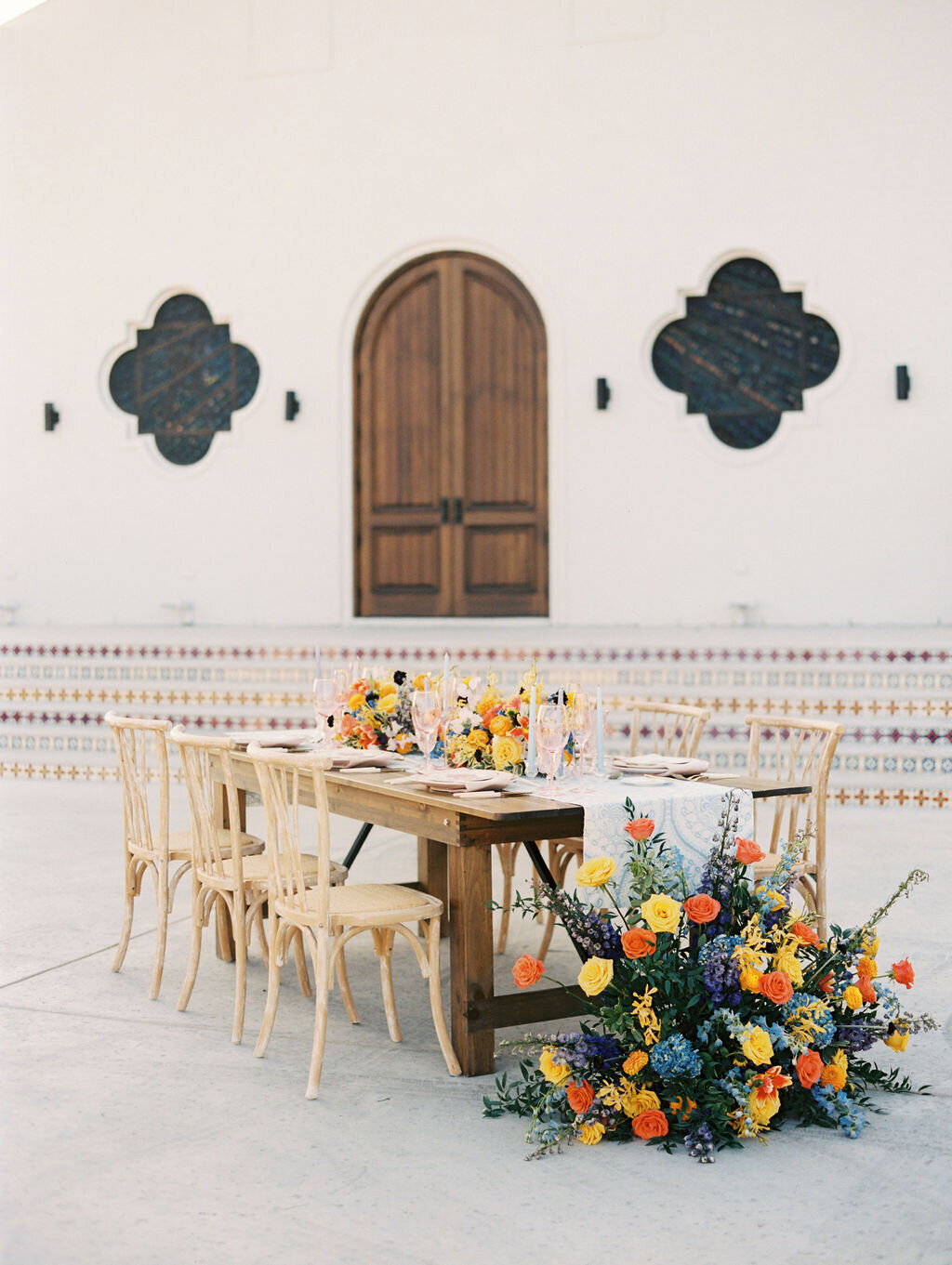 outdoor farm table at wedding with bright flowers and place settings