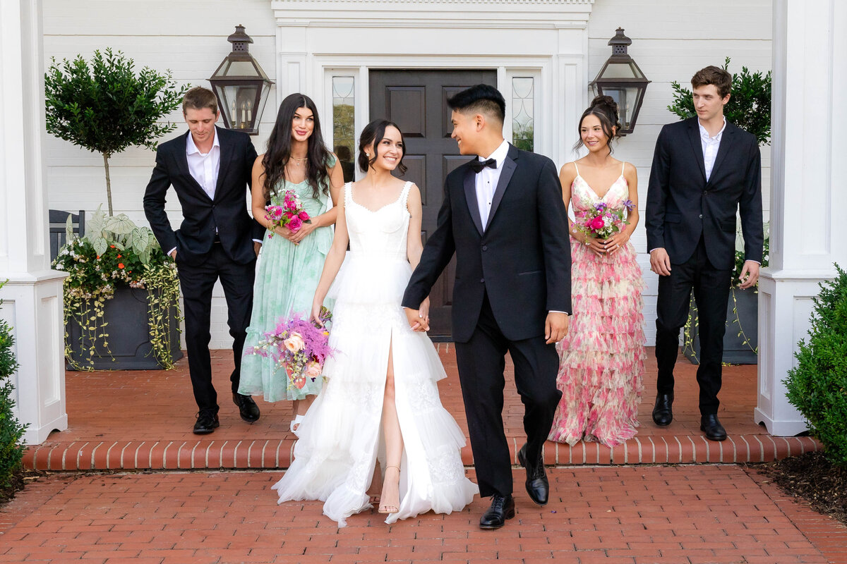 Bride and Groom leaving their venue right after the ceremony.  Laughing and looking at each other with happiness as their wedding party follows closely behind with smiles on their faces.