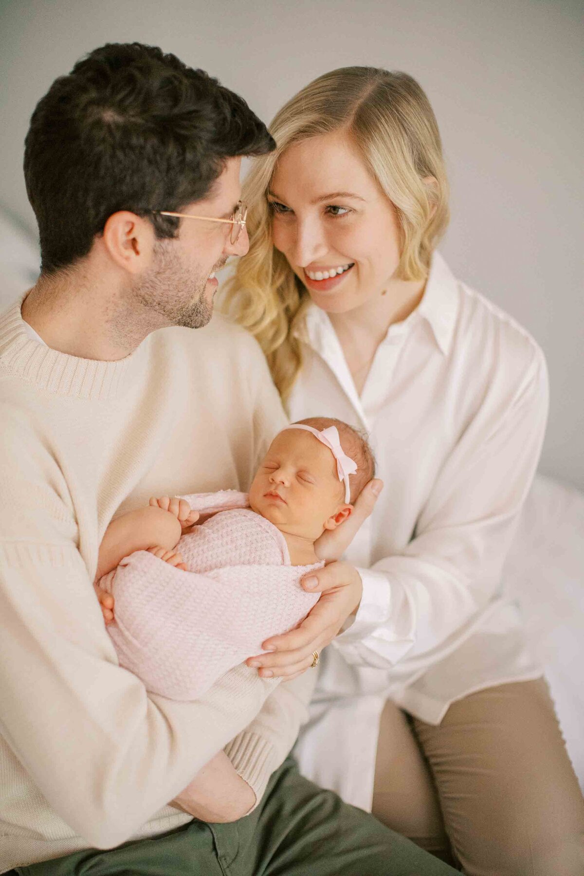 new mom and dad looking lovingly at each other while holding their new baby girl