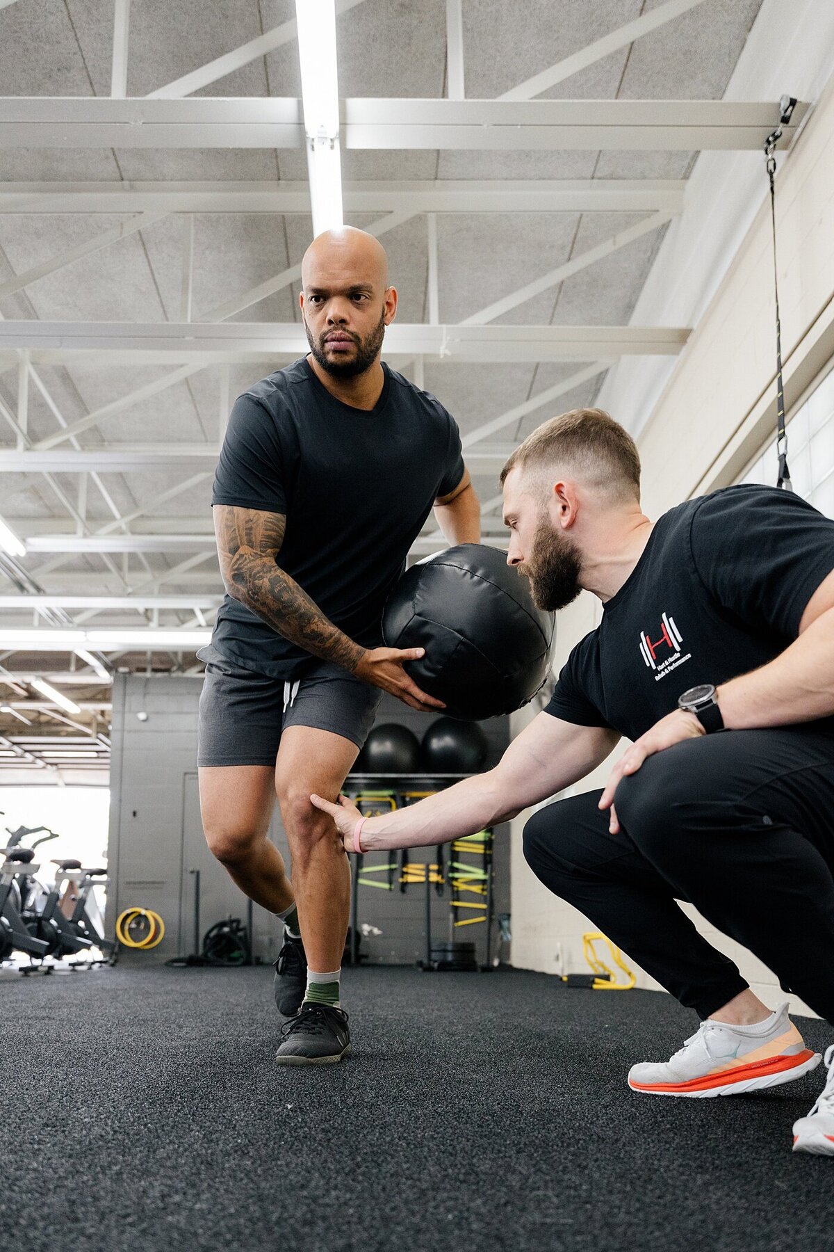 branding photos of personal trainer working with a client in the gym on their form by holding the mans knee photographed by Columbus photographer