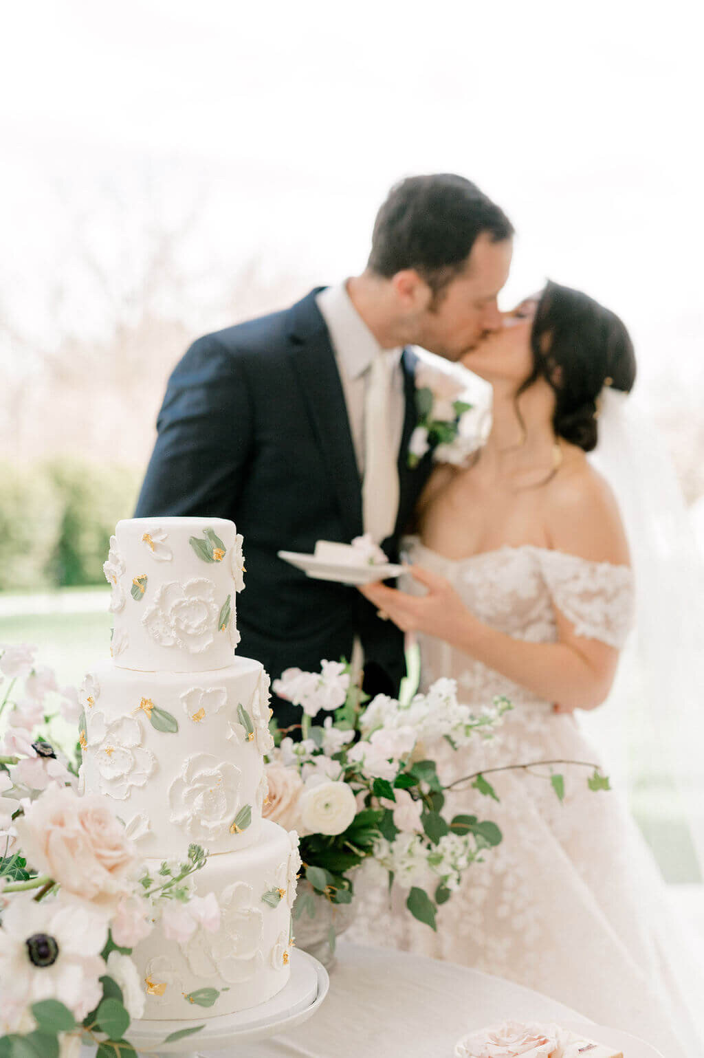 Bride and groom kissing in front of wedding cake for wedding photography by Virginia Photographer, Rachael Mattio