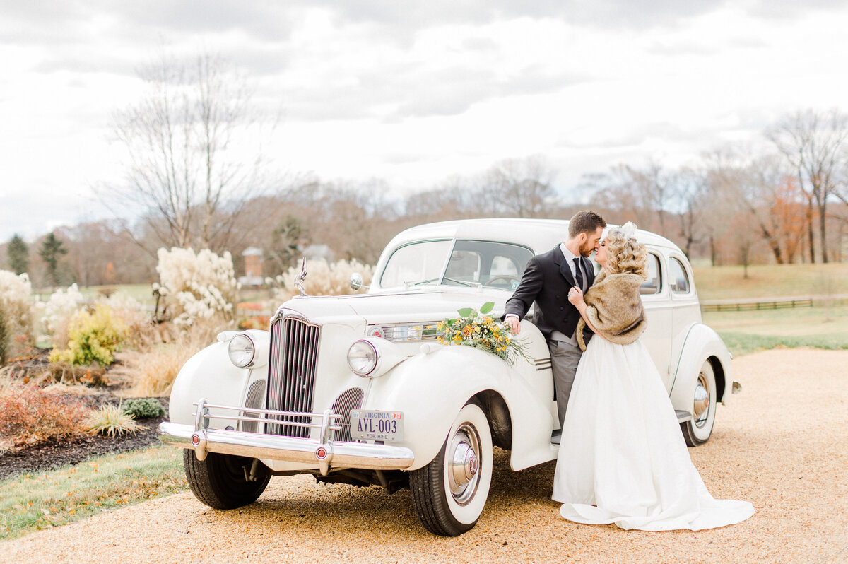 Bride and groom pose for a photo with old fashioned getaway car for Virginia wedding