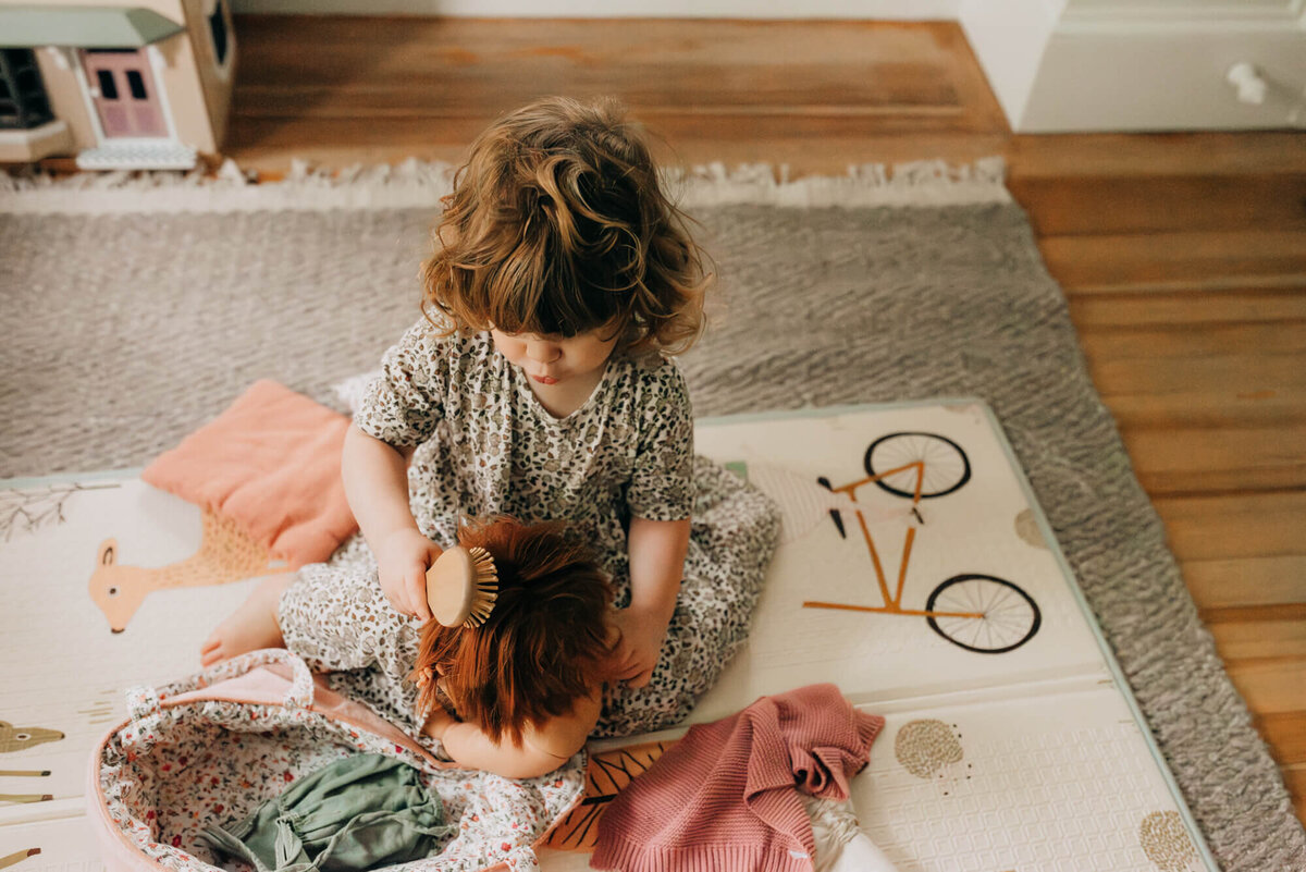 A toddler brushes her dolls hair in her nursery