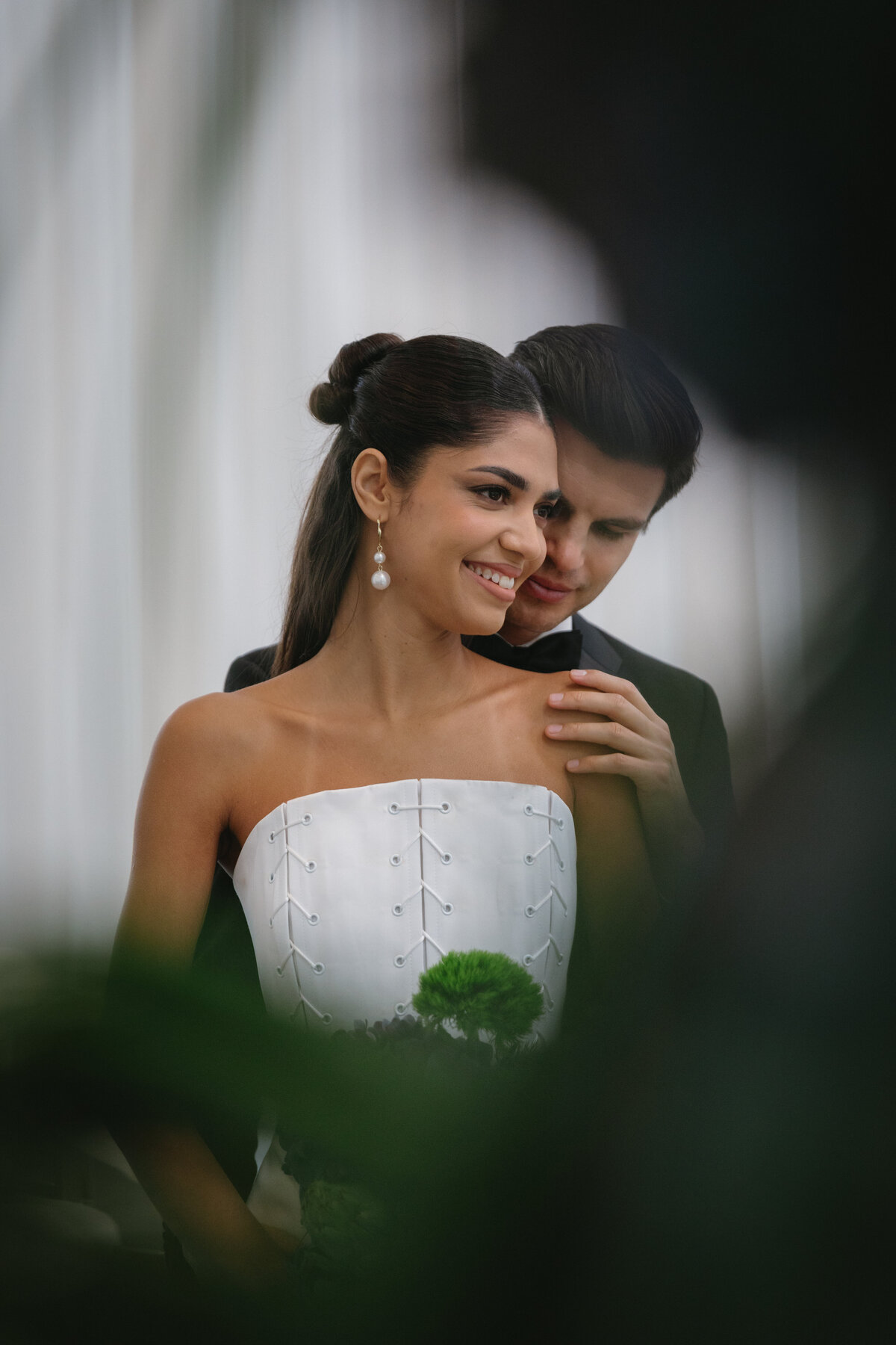 Couple standing together during an editorial NYC wedding shoot, surrounded by clean white drapery and modern seating.