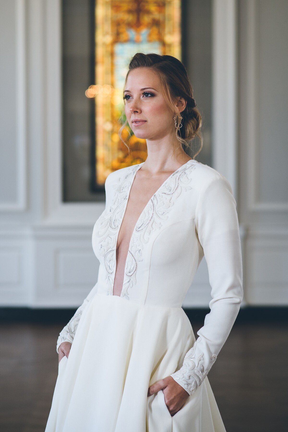 Iman is a long sleeve wedding dress with pockets and a plunging neckline in a wool crepe.