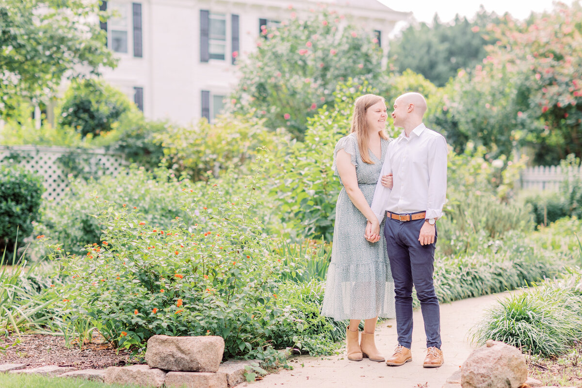 engaged couple holding hands in garden with bushes