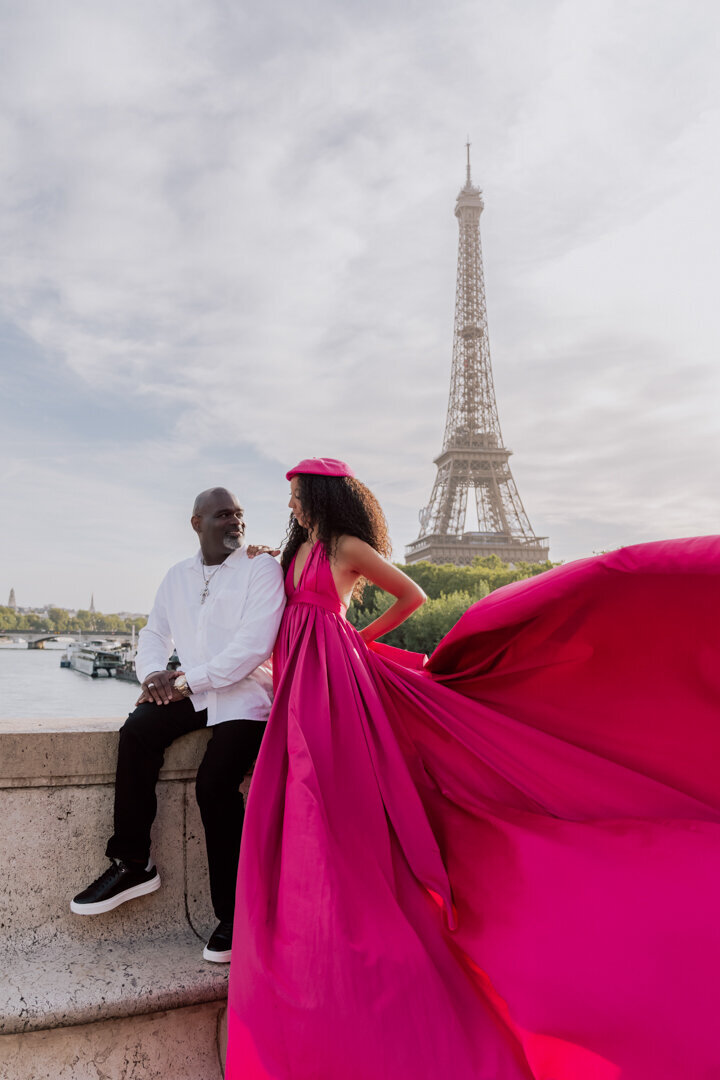 Paris couple portrait on wall, pink flying dress with matching beret, Eiffel Tower backdrop