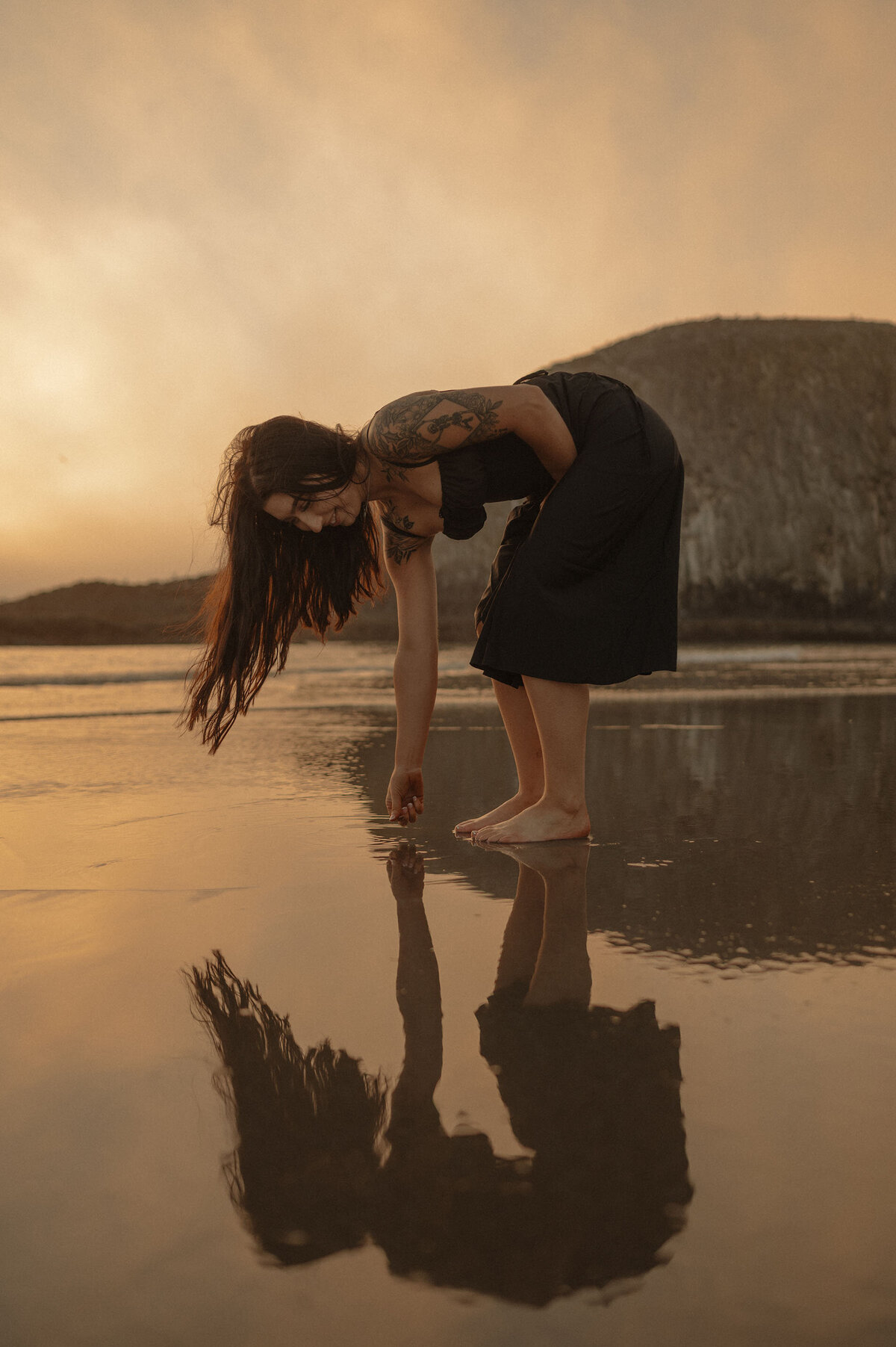 woman picks up rocks and shells along the shoreline at the Oregon Coast