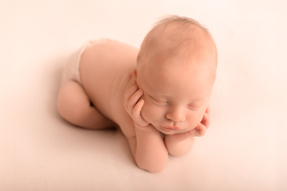 nyfödd bebis poserad i froggy pose