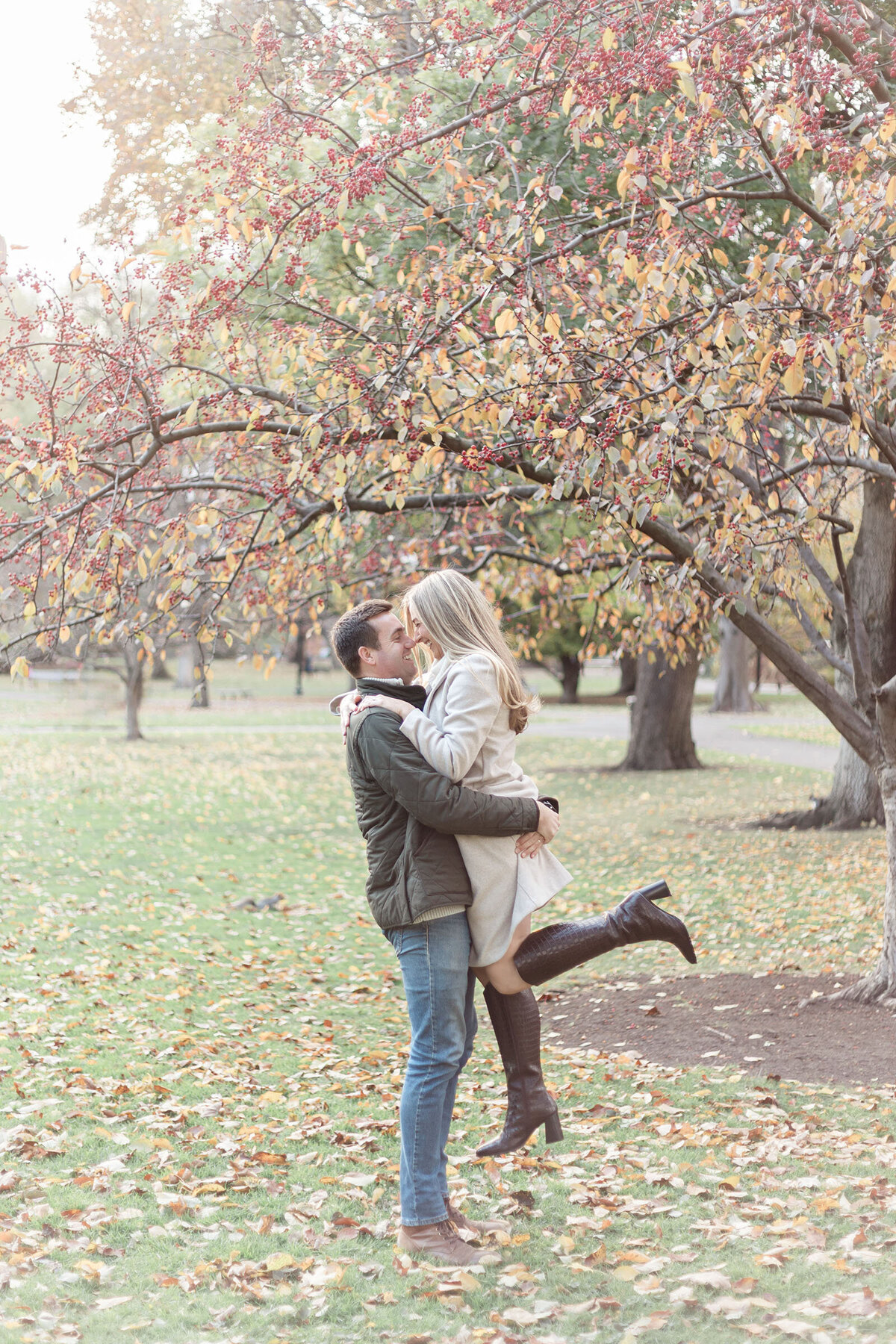 Man lifts his fiancee during their fall engagemnet sessison in Boston