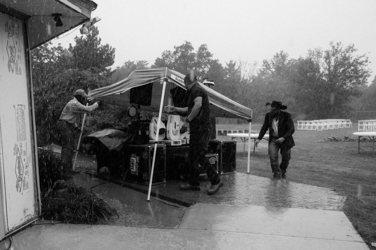 men-scramble-to-cover-DJ-equipment-in-rain
