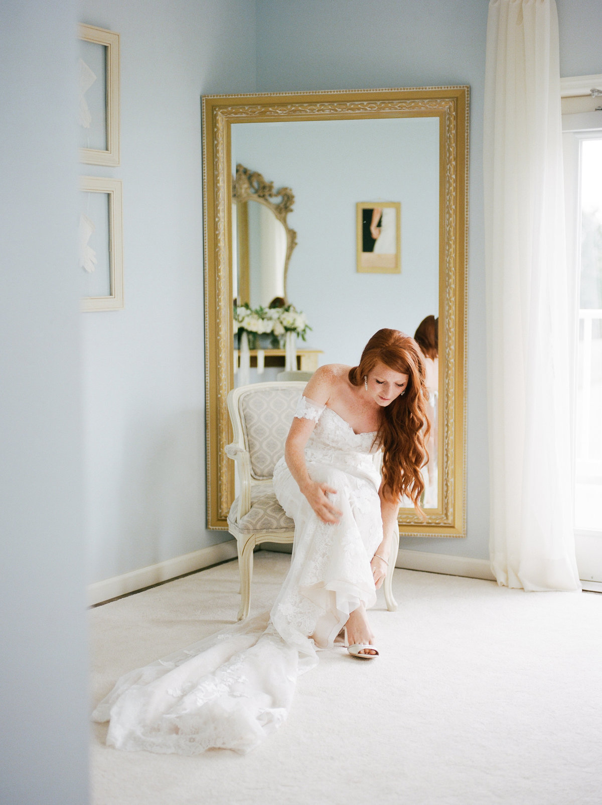 bride sitting on chair putting bridal shoes on while getting ready