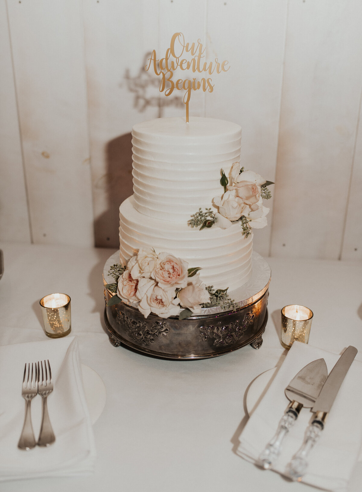 two tier wedding cake with a knife and server with two gold
