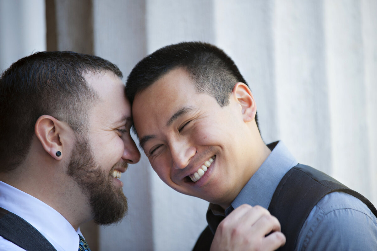 A person leaning their head on their partner's as they laugh 