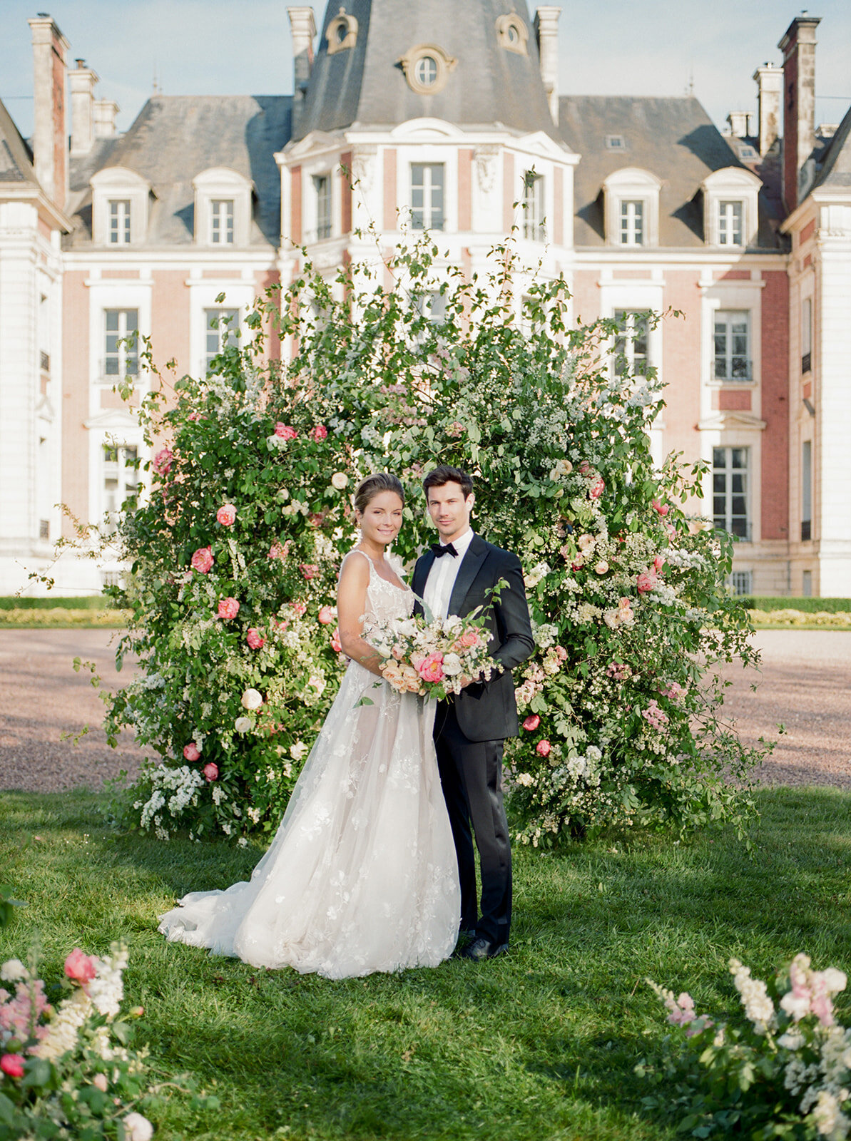 les mariés devant l'arche fleurie