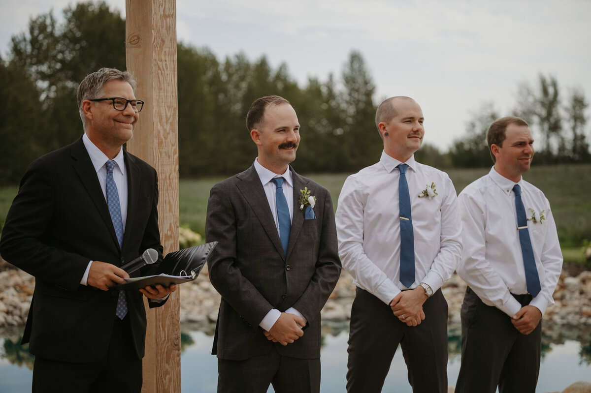 groom smiling at bride as she walks down aisle
