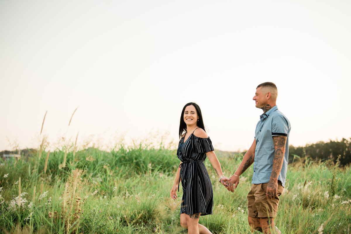 couple-man-women-walking-in-long-grassy-field-at-sunset-lead-images