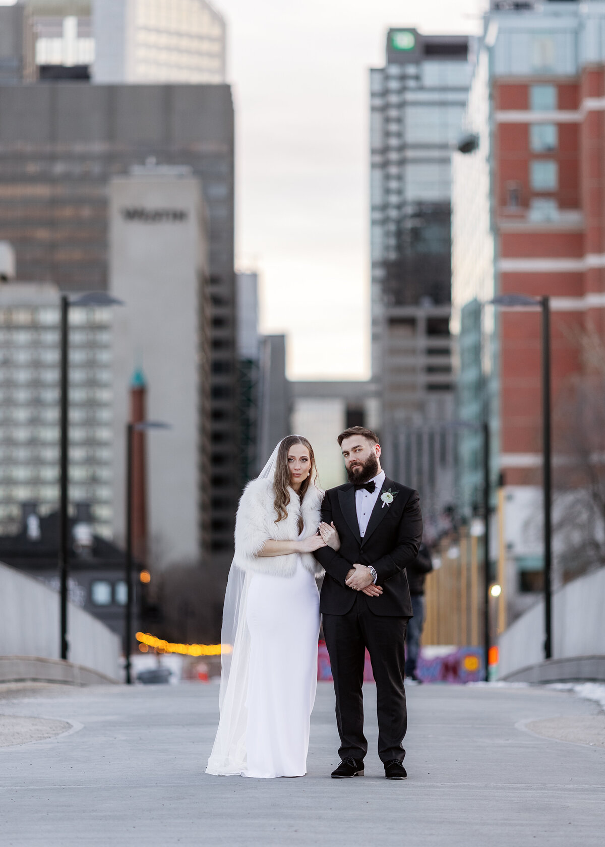 Bride and groom pose for a portrait downtown during a winter wedding