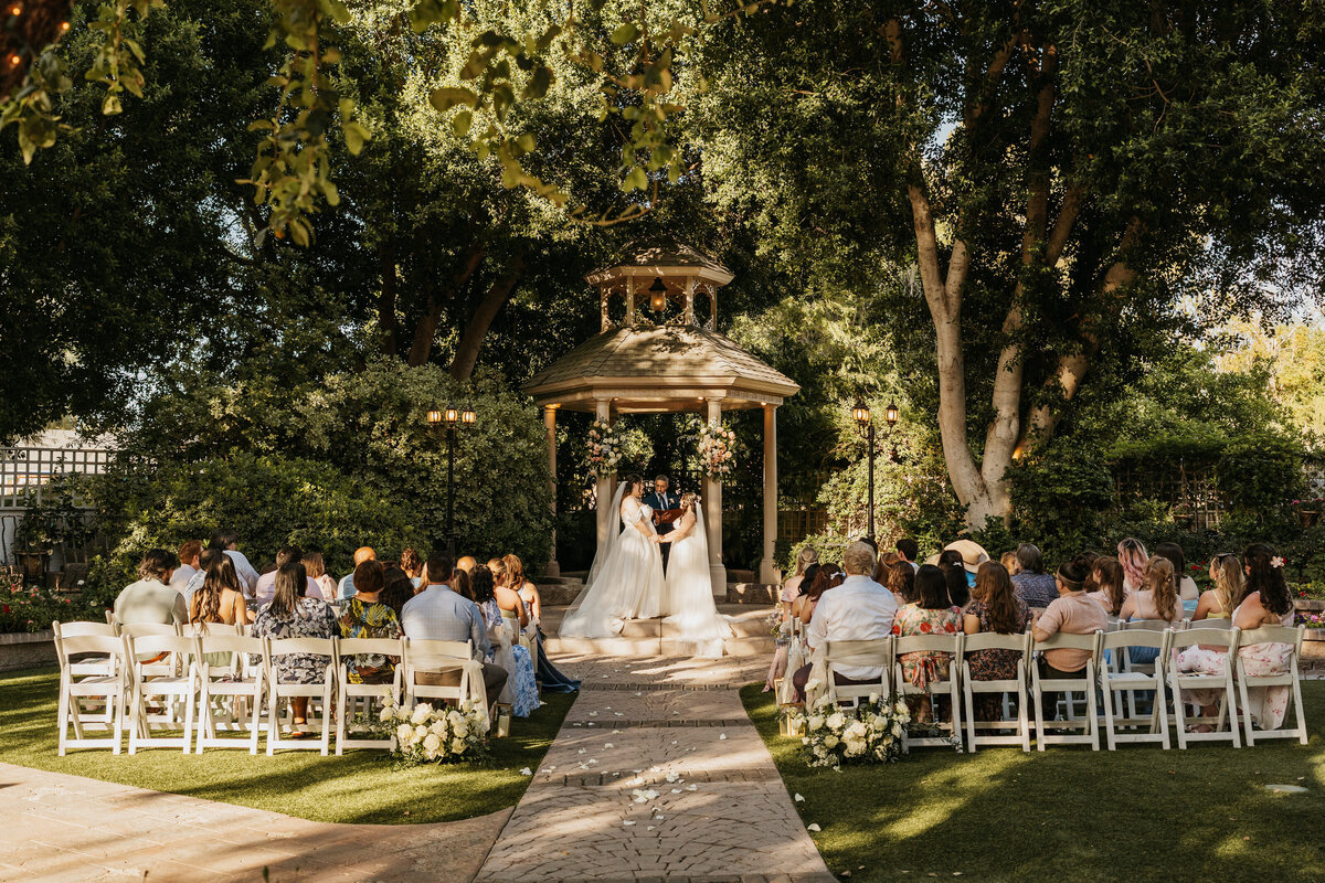 A couple holding hands as they say their vows in a garden wedding 