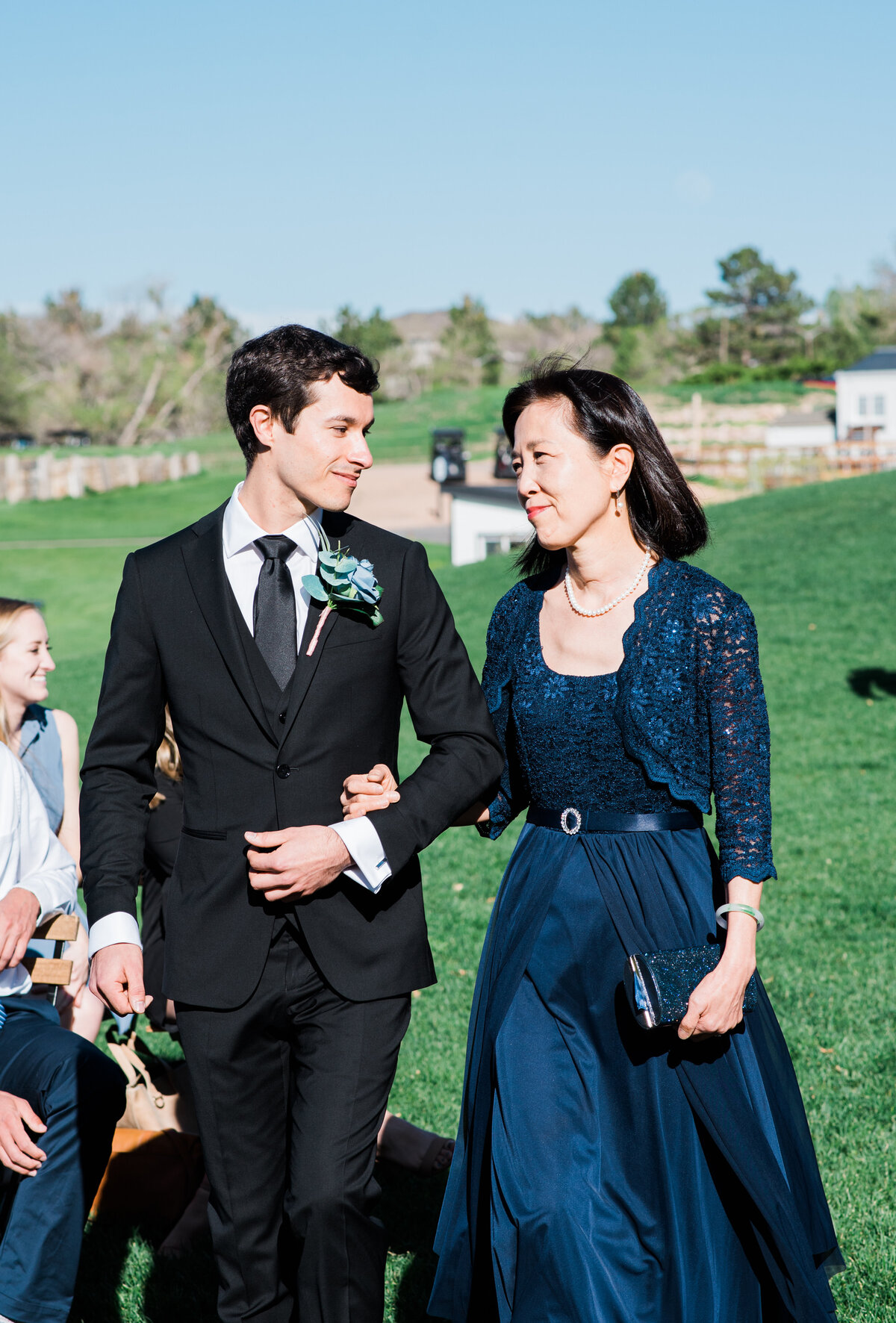 A groom walks down the isle with his mother in law-arm-in-arm-before the ceremony begins-captured by Denver wedding photographer