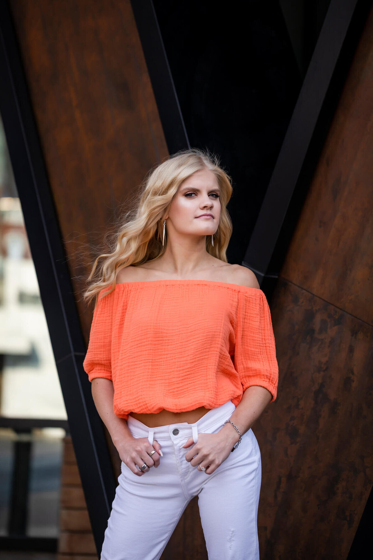 Striking senior portrait of a girl in an orange top. Captured by Springfield, MO senior photographer Dynae Levingston