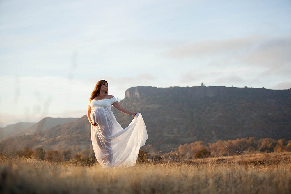 pregnant woman in flowy white dress at sunset near Tablerock