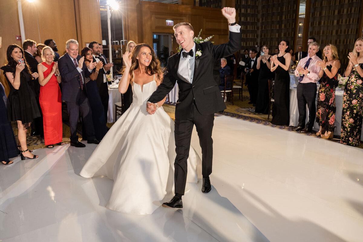 A bride and groom are walking down the aisle at their wedding reception