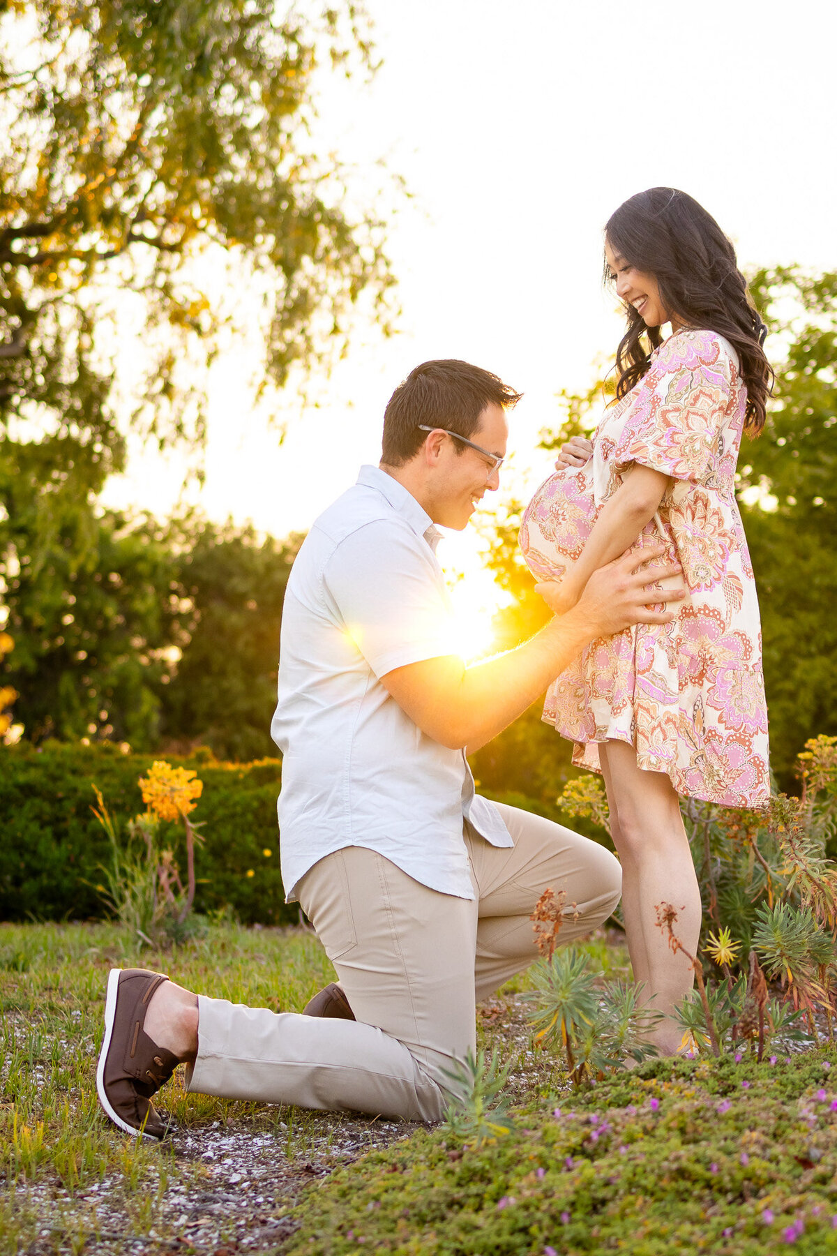 Golden hour glow surrounds a joyful maternity moment as expecting couple smiles at each other in the garden — Bay Area Maternity Portfolio - Ellobelle Photography.