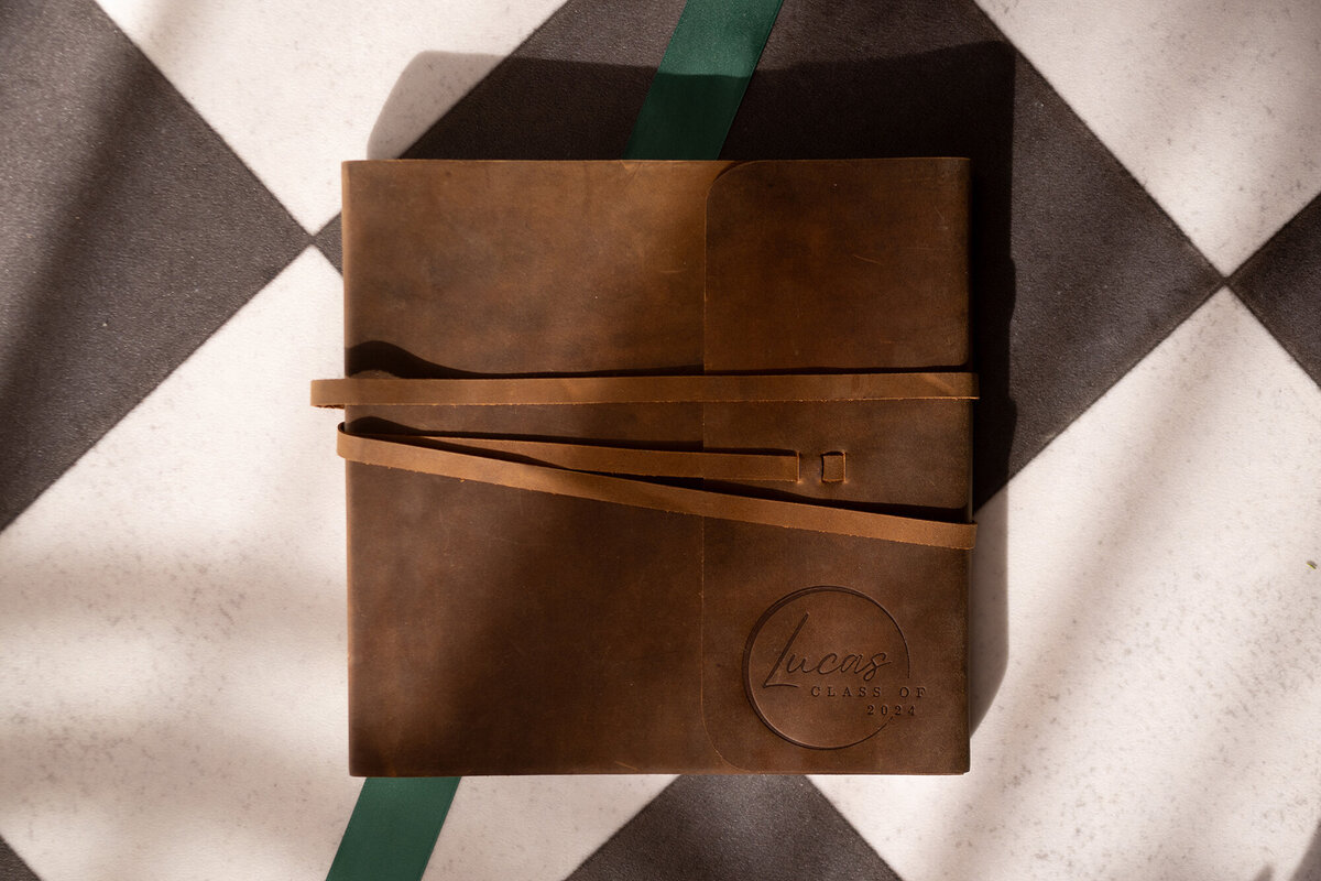 A brown leather photo album lays on a table with binding