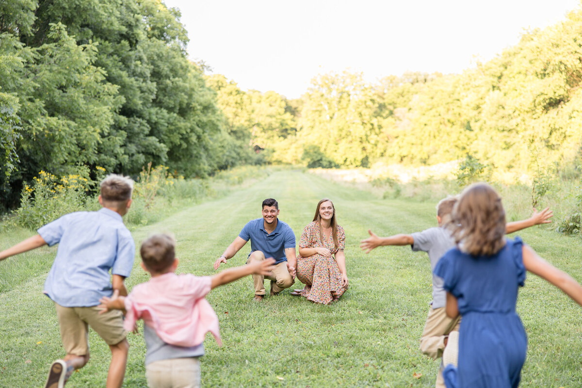 kids run to mom and dad with open arms in a field at Phillips Park in Beavercreek, Ohio.