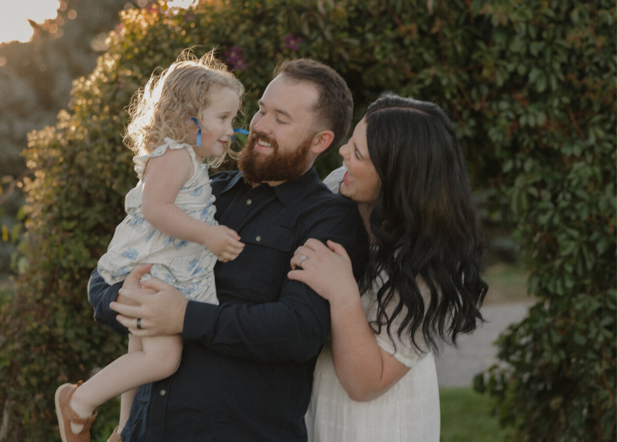 Candid photo of Brigette and Michael holding and looking at their daughter Isabella.