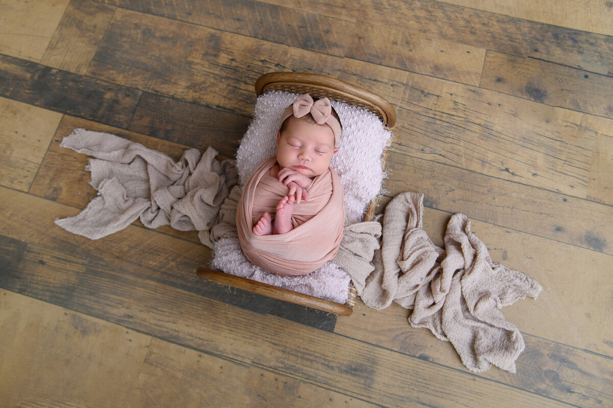 newborn girl wrapped in a tiny bed for her newborn photos 