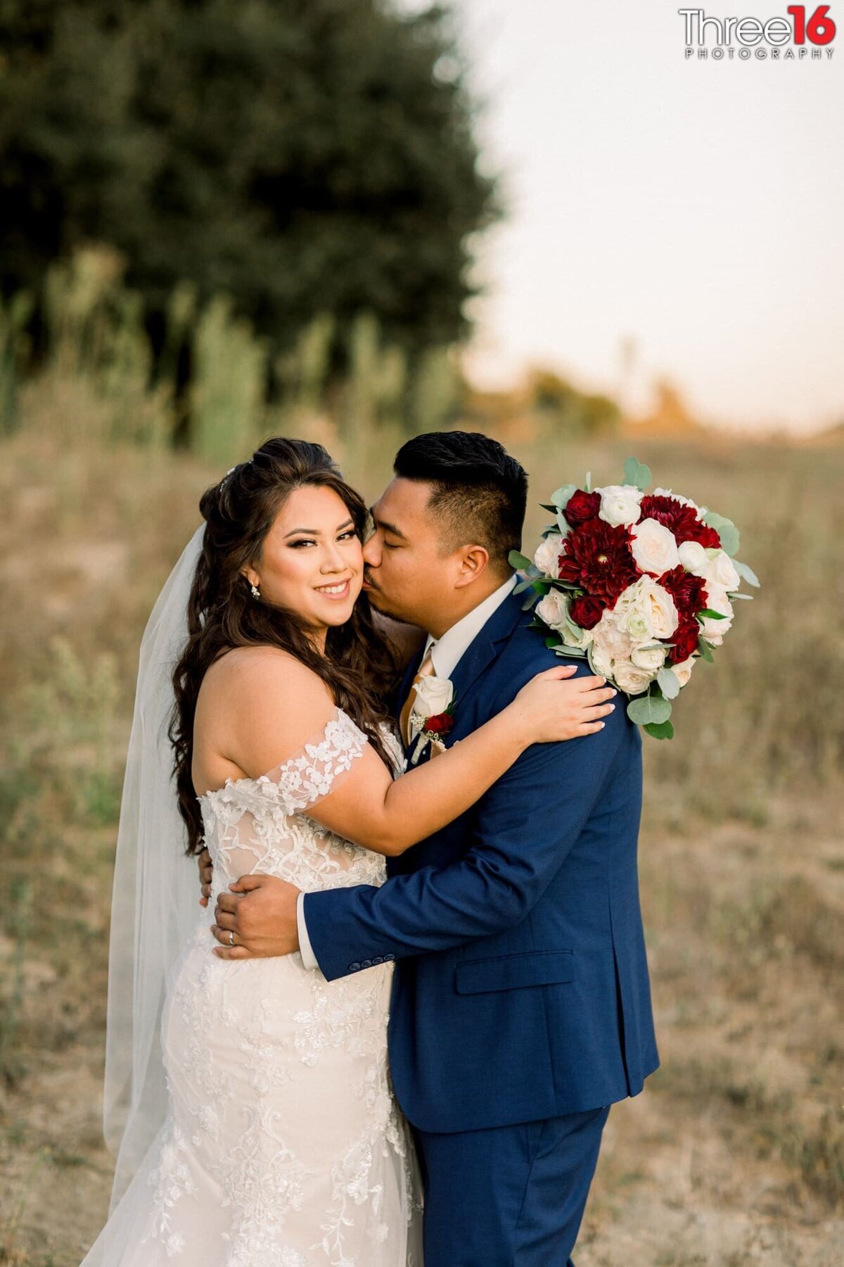 Groom kisses his Bride on the cheek as they embrace