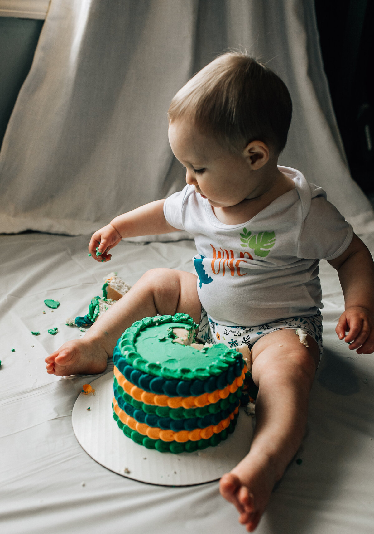 Baby sits on the floor with cake.