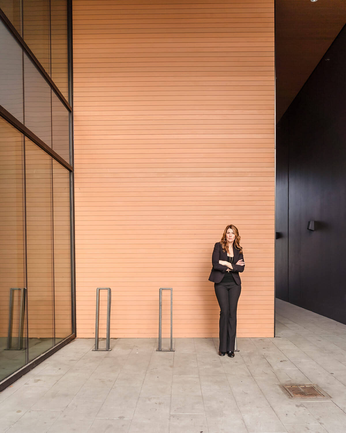 Woman posing outdoors against modern building wall during personal branding photoshoot wide angle shot