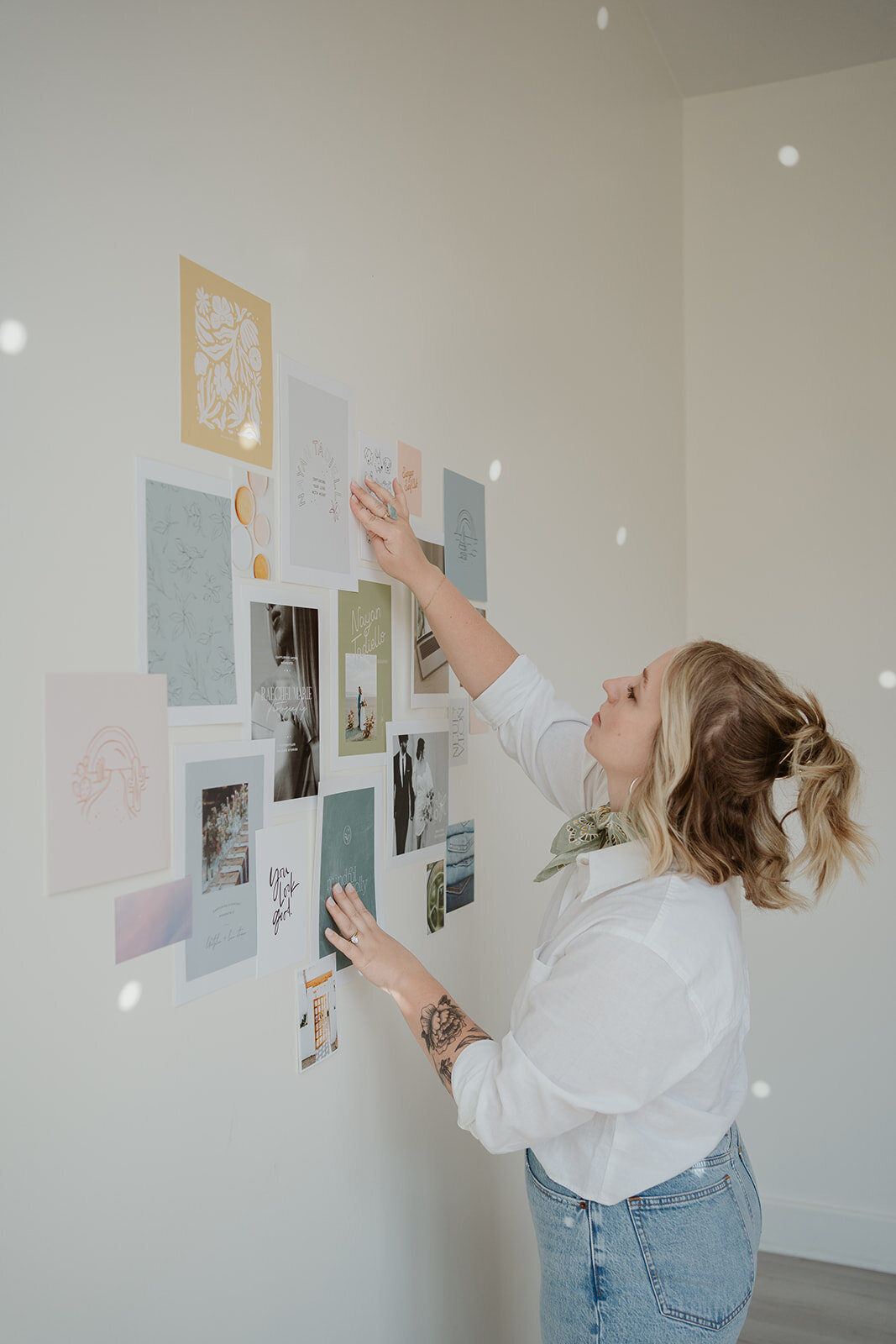 Close-up photo of a woman adjusting artwork on a studio mood board wall during a Wildher and Co branding session.