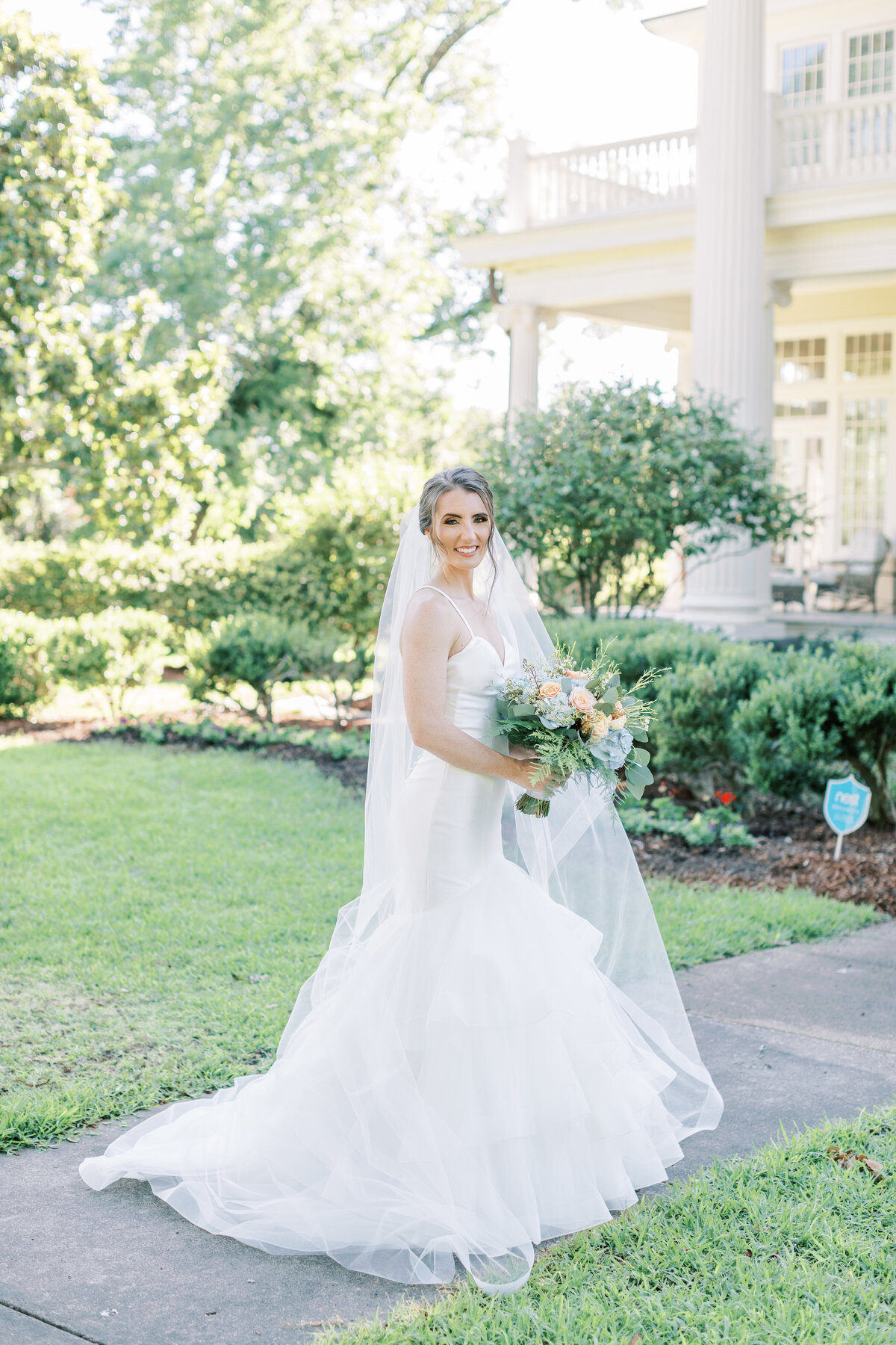 A bride wears her mermaid style dress while holding her bouquet.